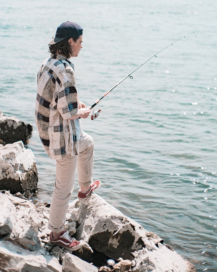 A guy fishes off the rocks.