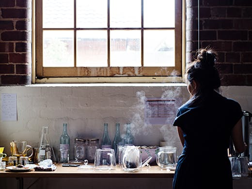 A woman making tea in a warehouse.