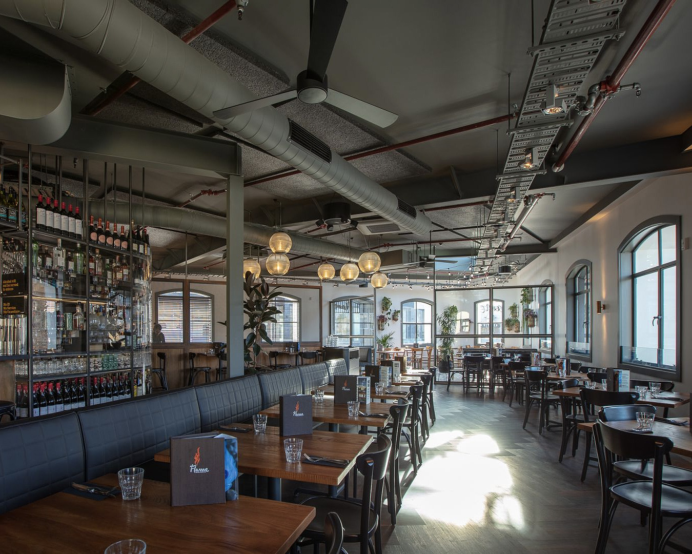 The interior at Flame Queenstown shows a beautiful dining room with light streaming through the windows.