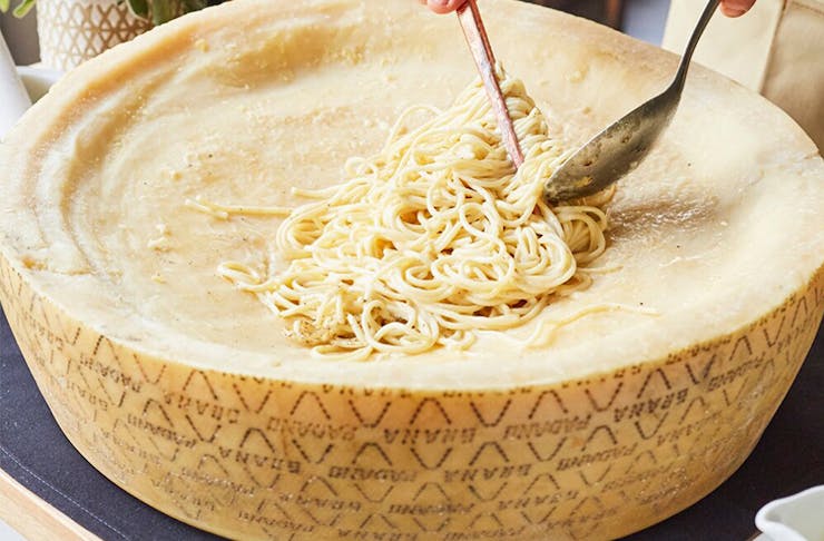 a giant cheese wheel with pasta in it