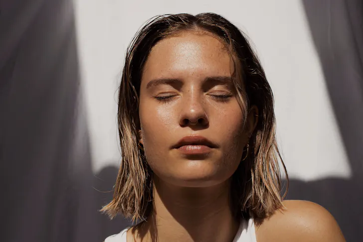 A lady with fresh clean skin and her eyes closed.