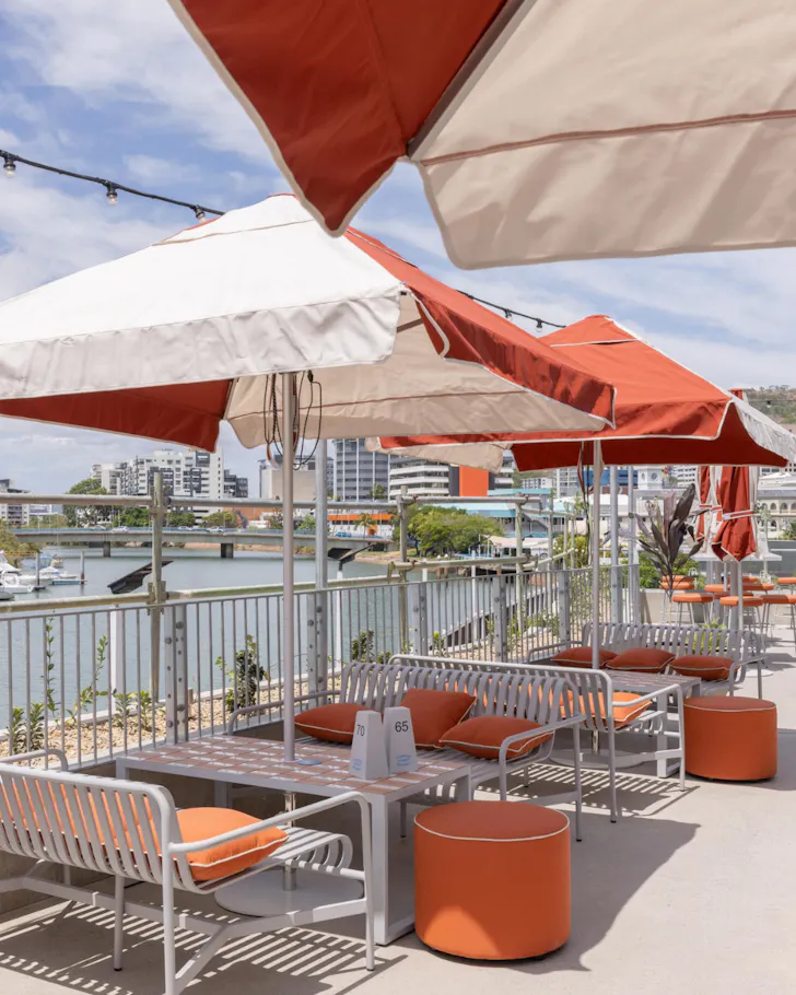 Striped umbrellas and seating by the river at Flinders Street Wharves.