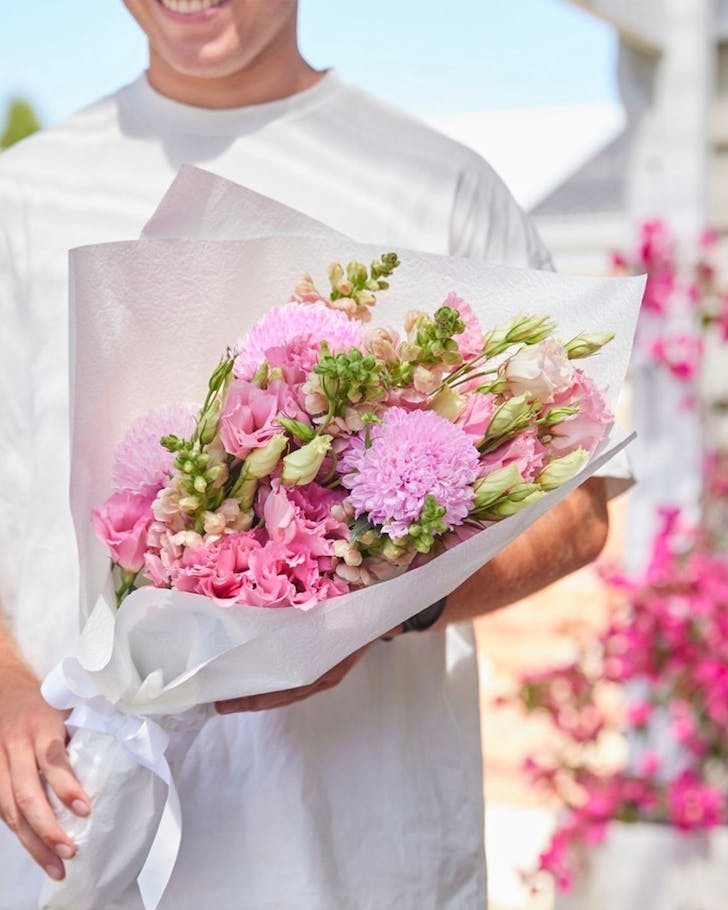 A person holds a bunch of pink flowers from LVLY one of the best flower delivery services in Perth