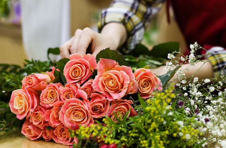 A woman carefully arranges a bunch of colourful flowers.