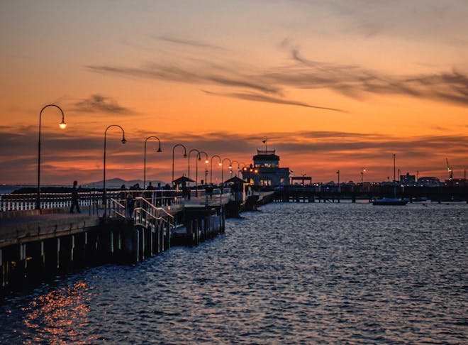 A St Kilda jetty soaked in orange hues at sunset.