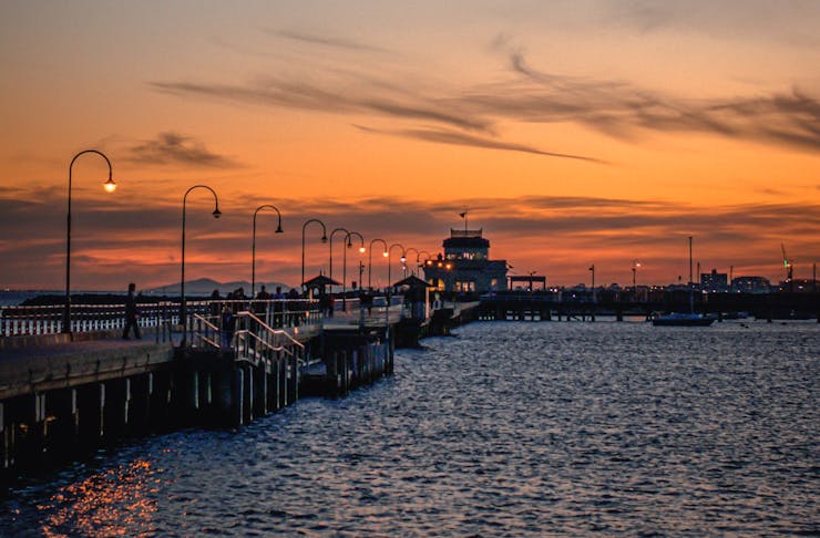 A St Kilda jetty soaked in orange hues at sunset.