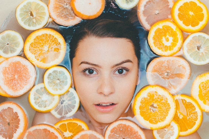 woman's face in bath surrounded by orange slices