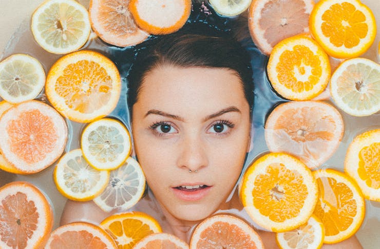 woman's face in bath surrounded by orange slices