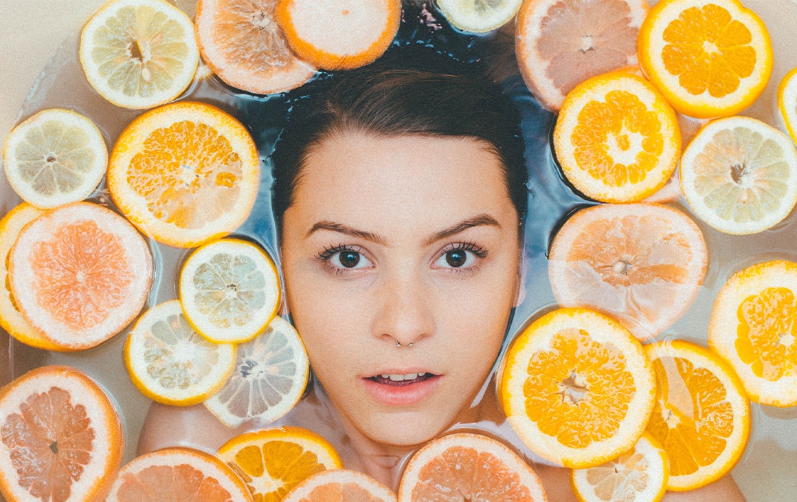 woman's face in bath surrounded by orange slices