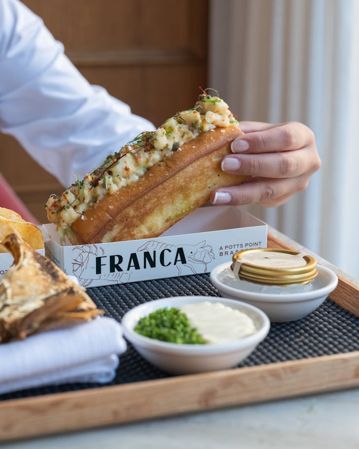 a woman picks up a brioche roll with moreton bay bug at sydney restaurant franca