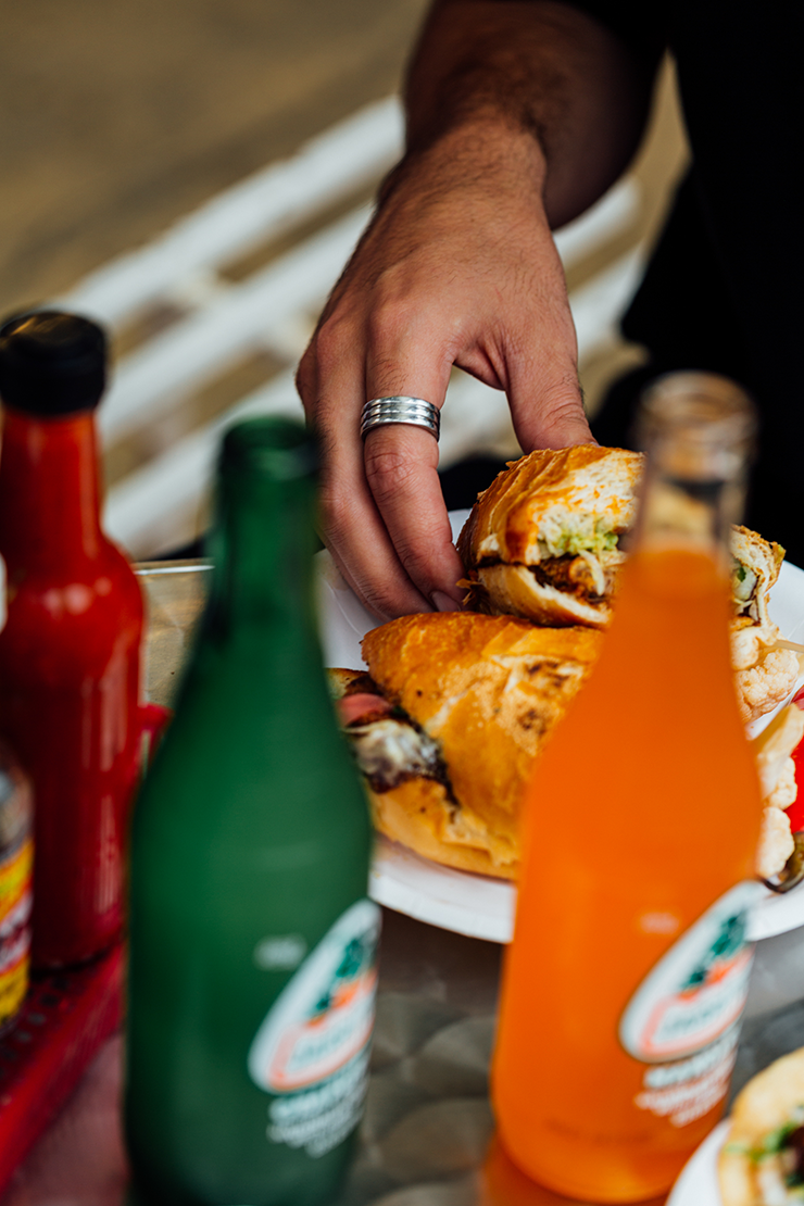 Hot sauce, Mexican soda and a torta from Frankie's stacked casually on a table.