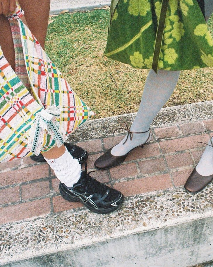 An image looking down at two girls' vintage shoes as they stand holding hand crafted fabric bags.