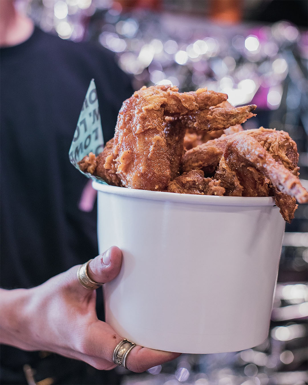 Someone holds a bucket of fried chicken.