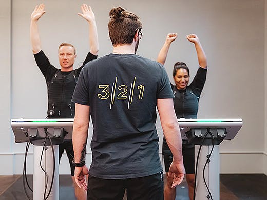 A personal trainer puts two people through their EMS training