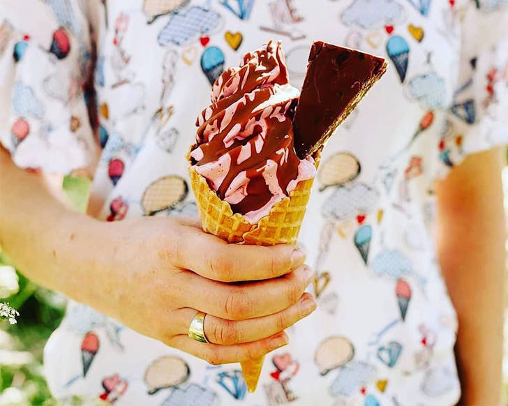 Someone holds a stacked looking ice cream cone at Fuse Real Fruit Ice Cream.