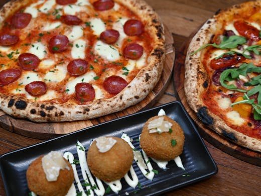 two pizzas and a plate of arancini
