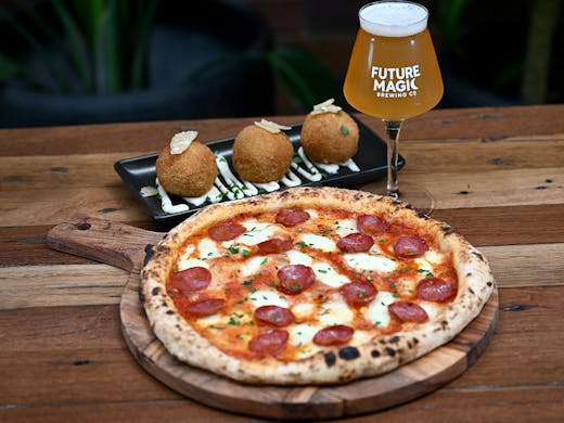 a light beer, a pizza and a plate of arancini