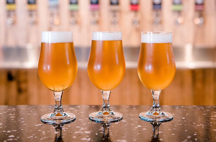 three beers in glasses on a bar