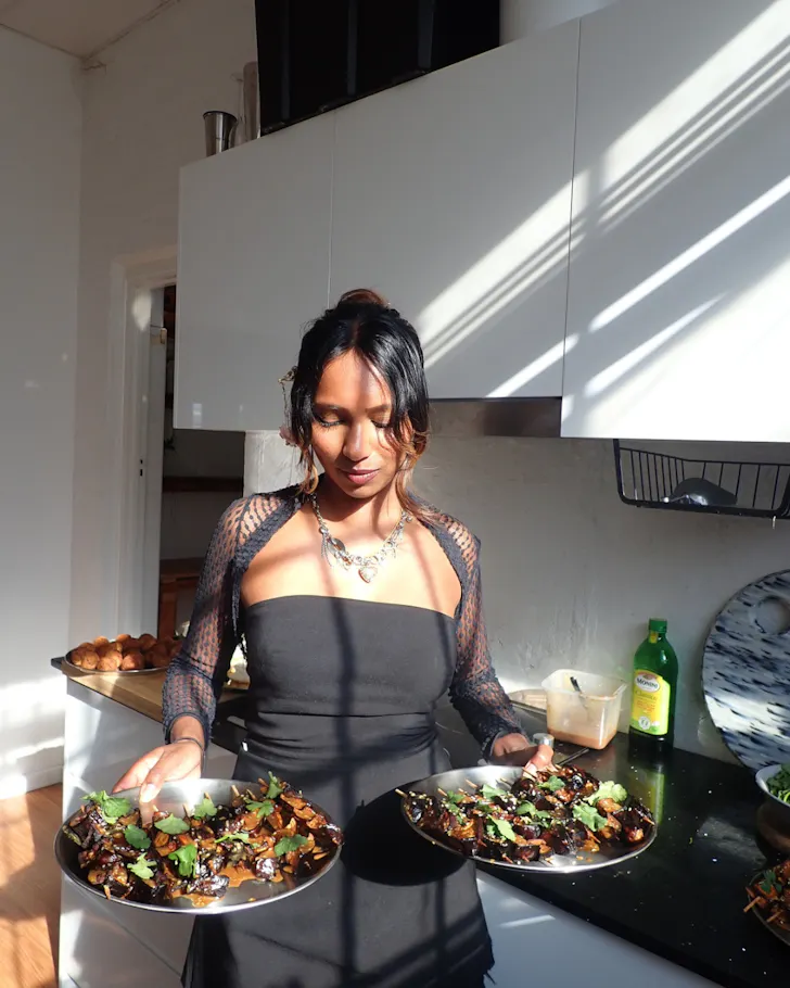 Gaya holding two dishes she has prepared.
