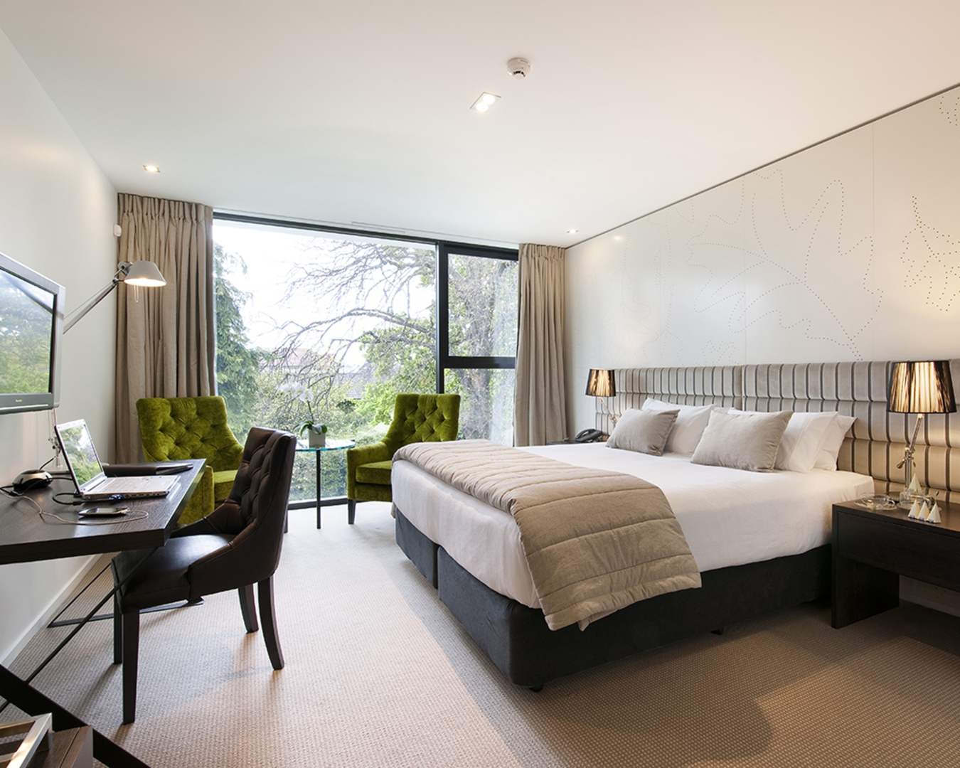 Bathed in natural light from a floor-to-ceiling window, this airy room at The George features a comfy bed and inviting seating area