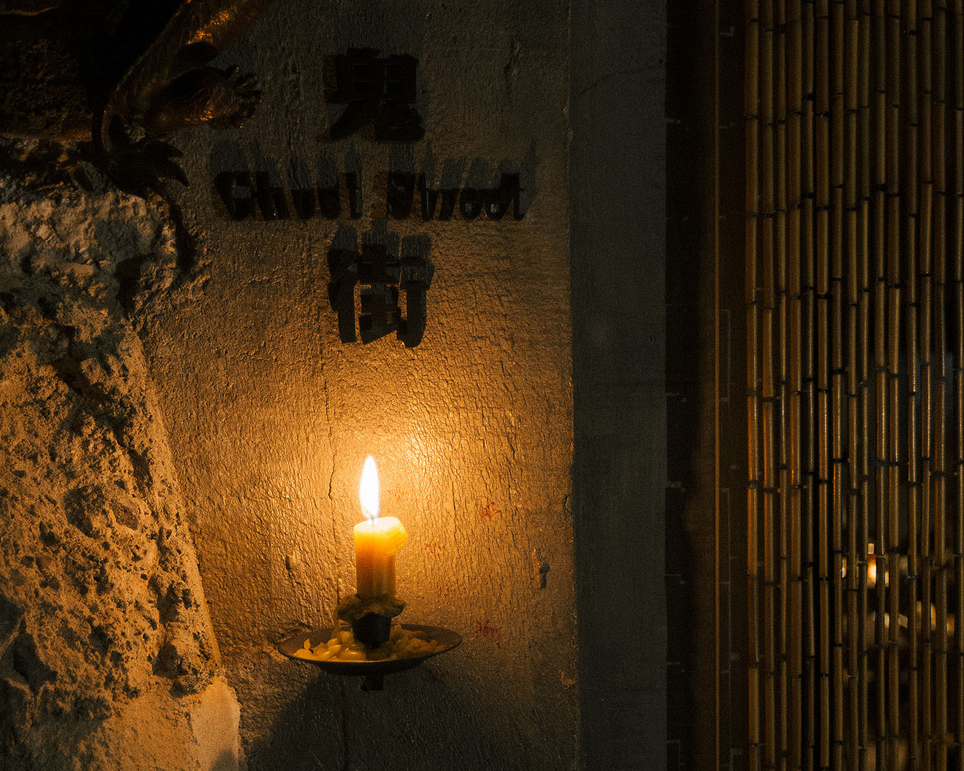 A candle on a concrete wall just lights a sign that reads ‘Ghost Street’. 
