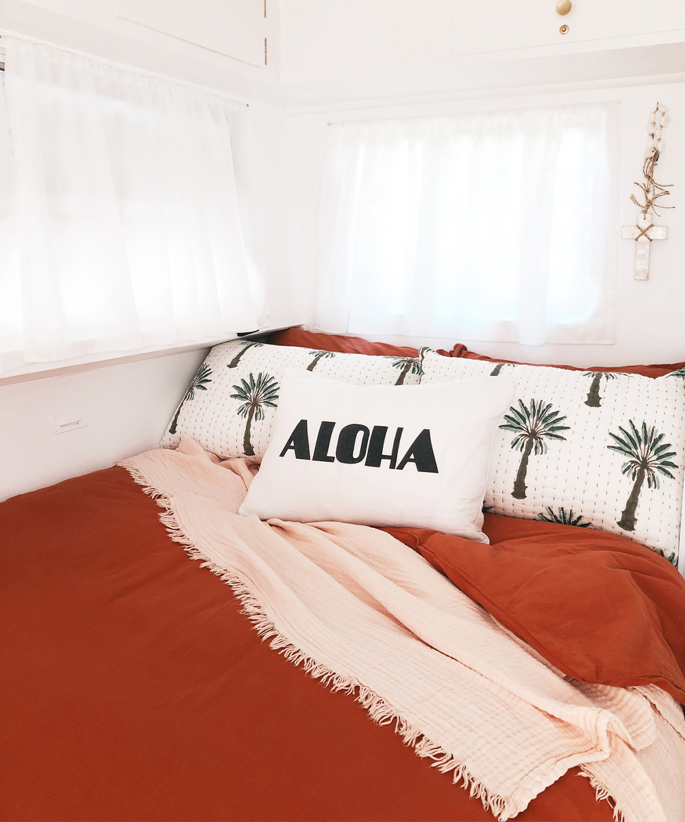 a bed made up wth pretty pillows in a caravan