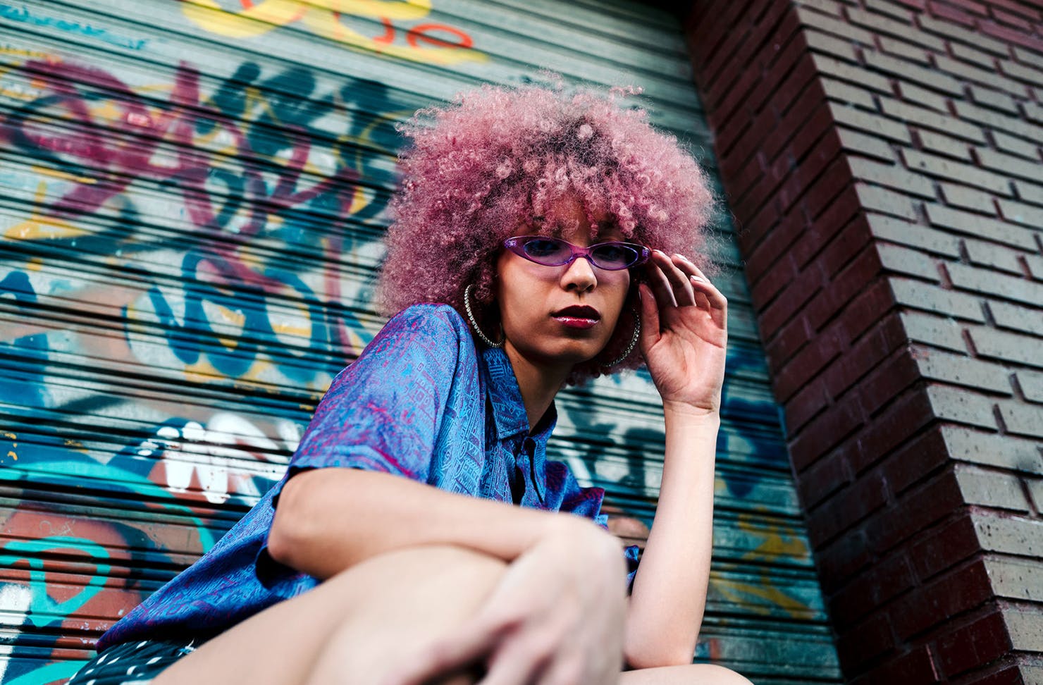 A girl poses outside a graffitied garage.