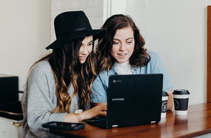 Girls look excitedly at a laptop, perhaps watching their shares go through the roof.