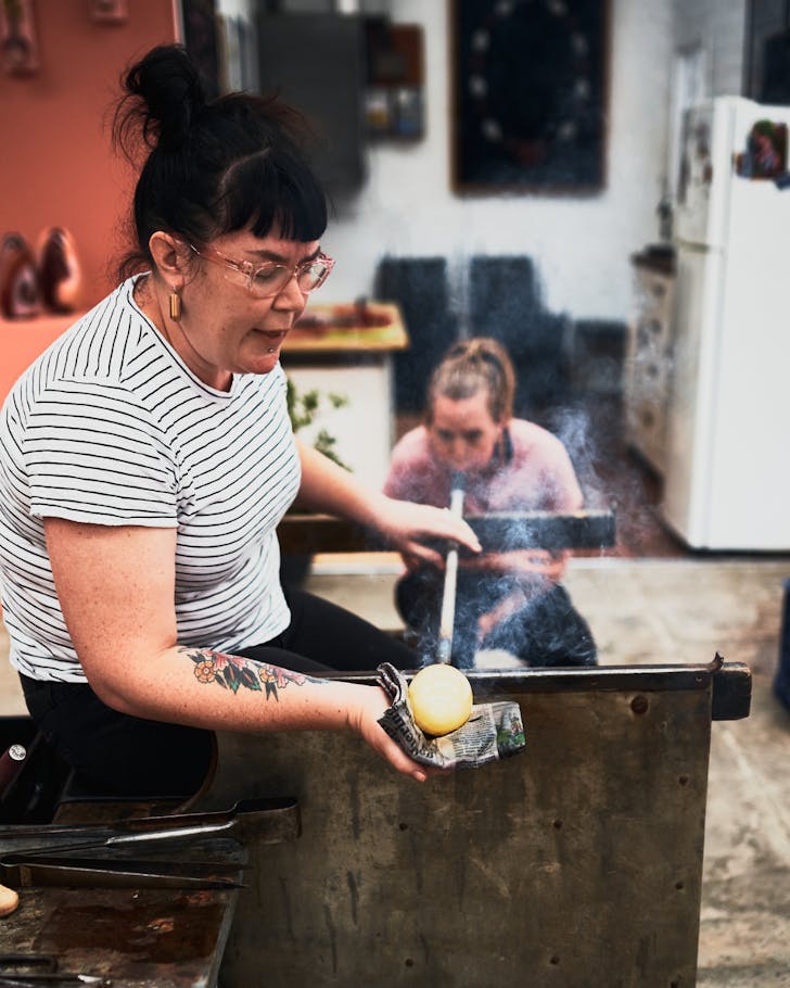 A woman demonstrates glassblowing