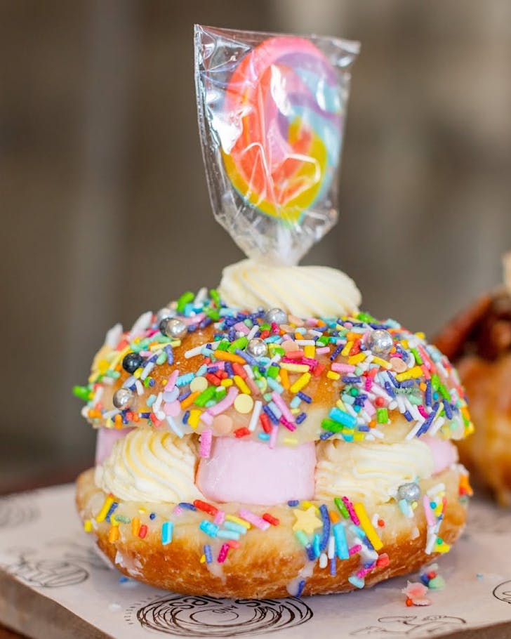A clam-shell-like donut with a creamy filling and topped with hundreds and thousands and other jovial sprinkles.