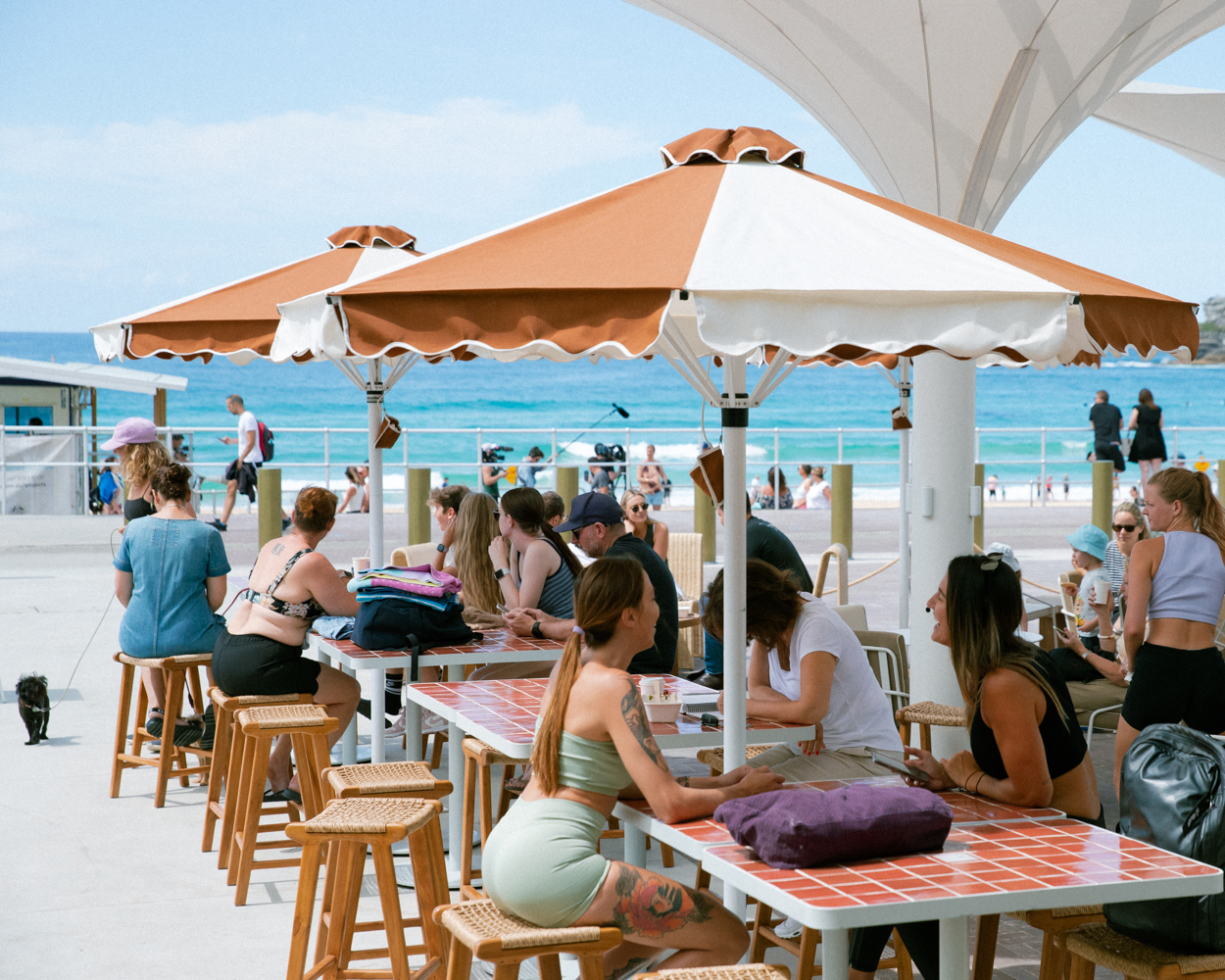 People sit under umbrellas at a cafe on Bondi Beach