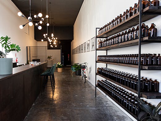 A long, minimally-designed wine bar with bottles on the right hand wall.