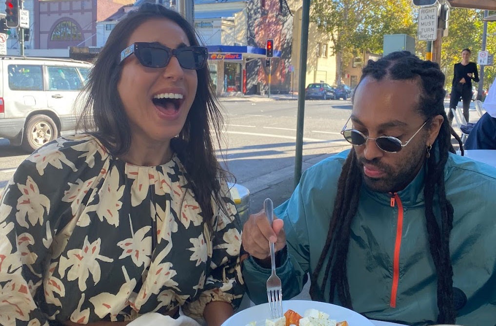 Two people at a cafe laughing and eating food. 
