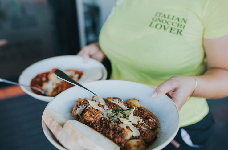 A waiter holding two bowls of gnocchi