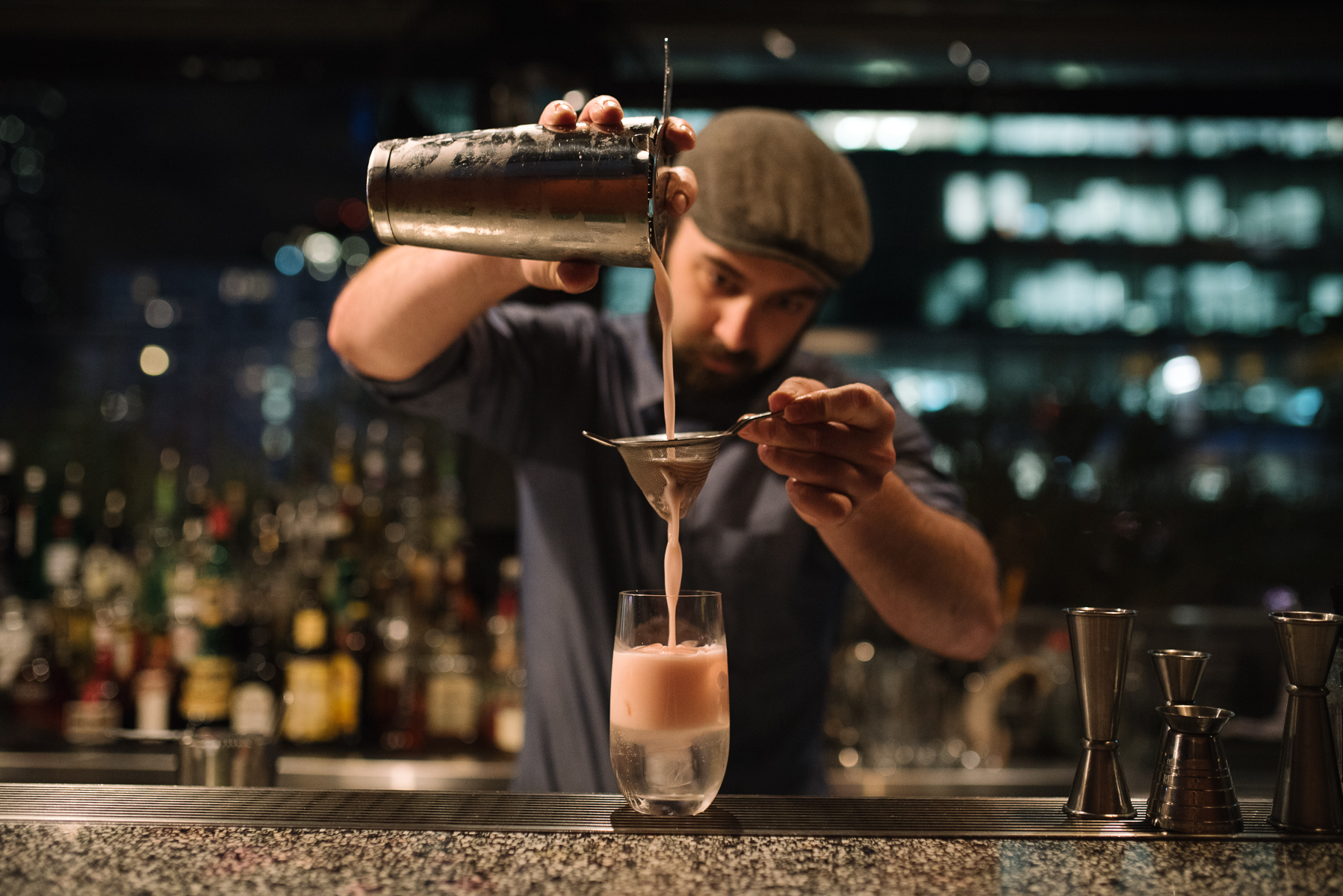 A person pouring a cocktail out of a shaker at one of the best bars of Melbourne. 