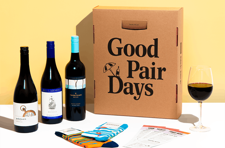 Three bottles of wine next to three pairs of socks and a box with the words 