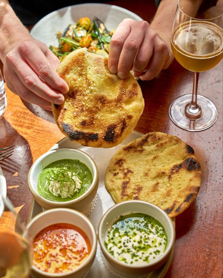 plate of three dips and hand using bread