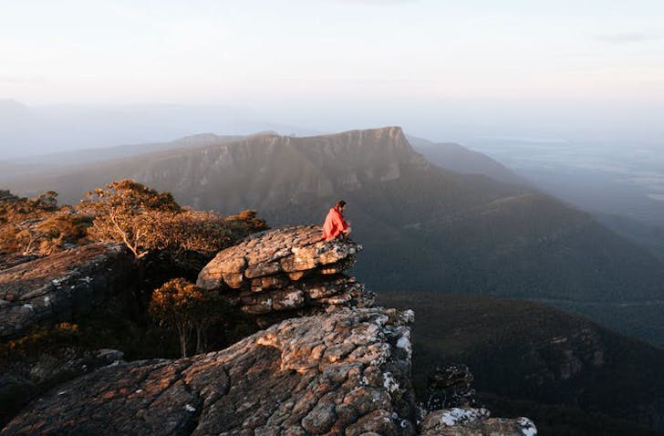 Someon hiking to the top of a cliff face in The Grampians.