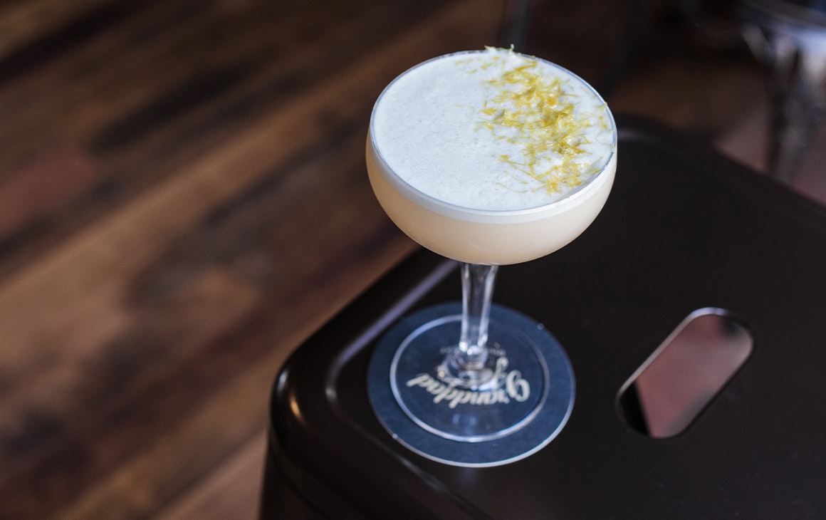 a yellow cocktail in a coupe glass