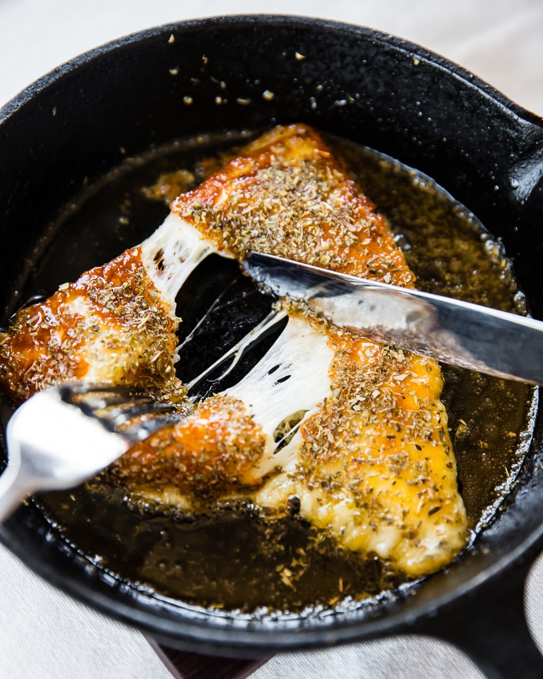 a piece of grilled cheese being pulled apart by forks