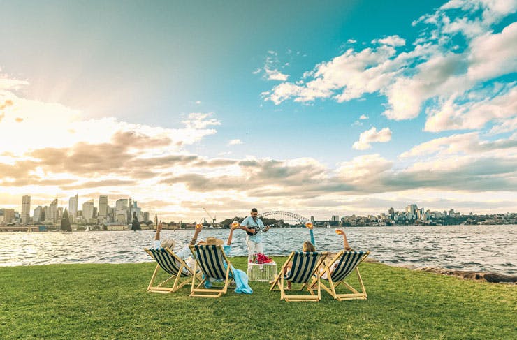 Deck chairs set up on green grass, overlooking Sydney Harbour. 