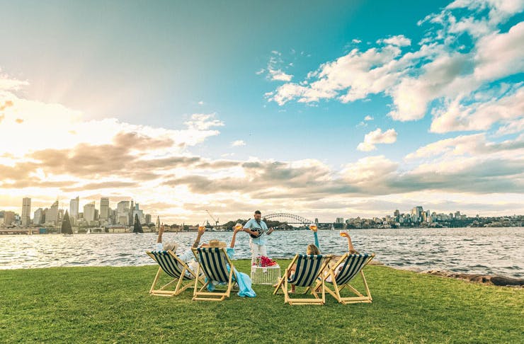 Deck chairs set up on green grass, overlooking Sydney Harbour. 