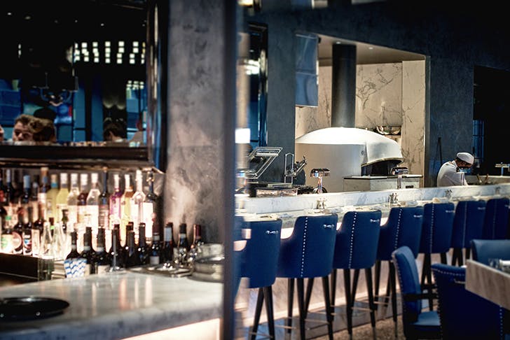 A bar with blue seats and marble benches. 