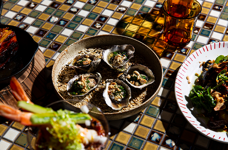 A serve of grilled oysters on a tiled table.