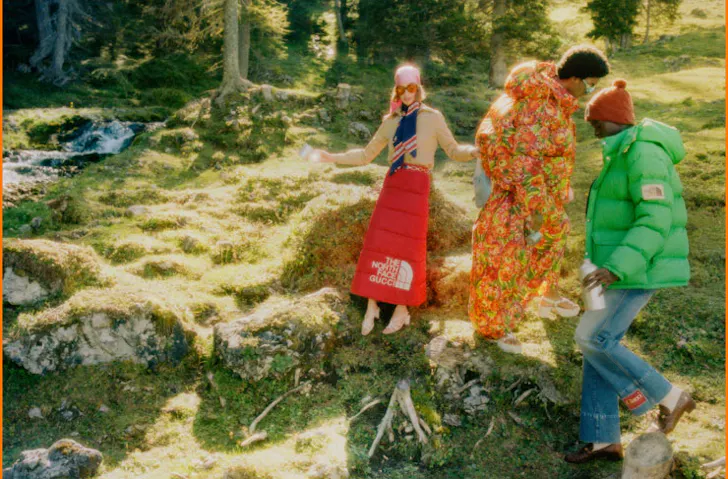 Three people dressed in The North Face x Gucci on a grassy hill. 