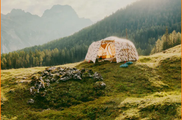 A tent on a grassy hill in the Alps. 