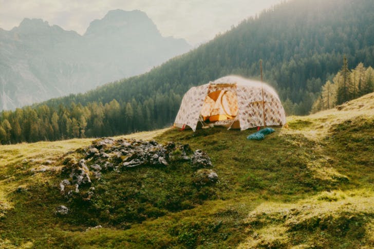 A tent on a grassy hill in the Alps. 