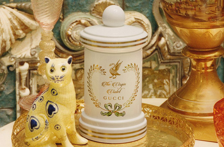 One of the best scented candles in an ornate ceramic casing and next to gold objects.