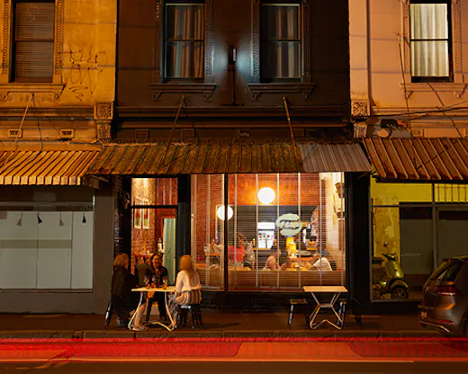 A small bar on a neon lit street.