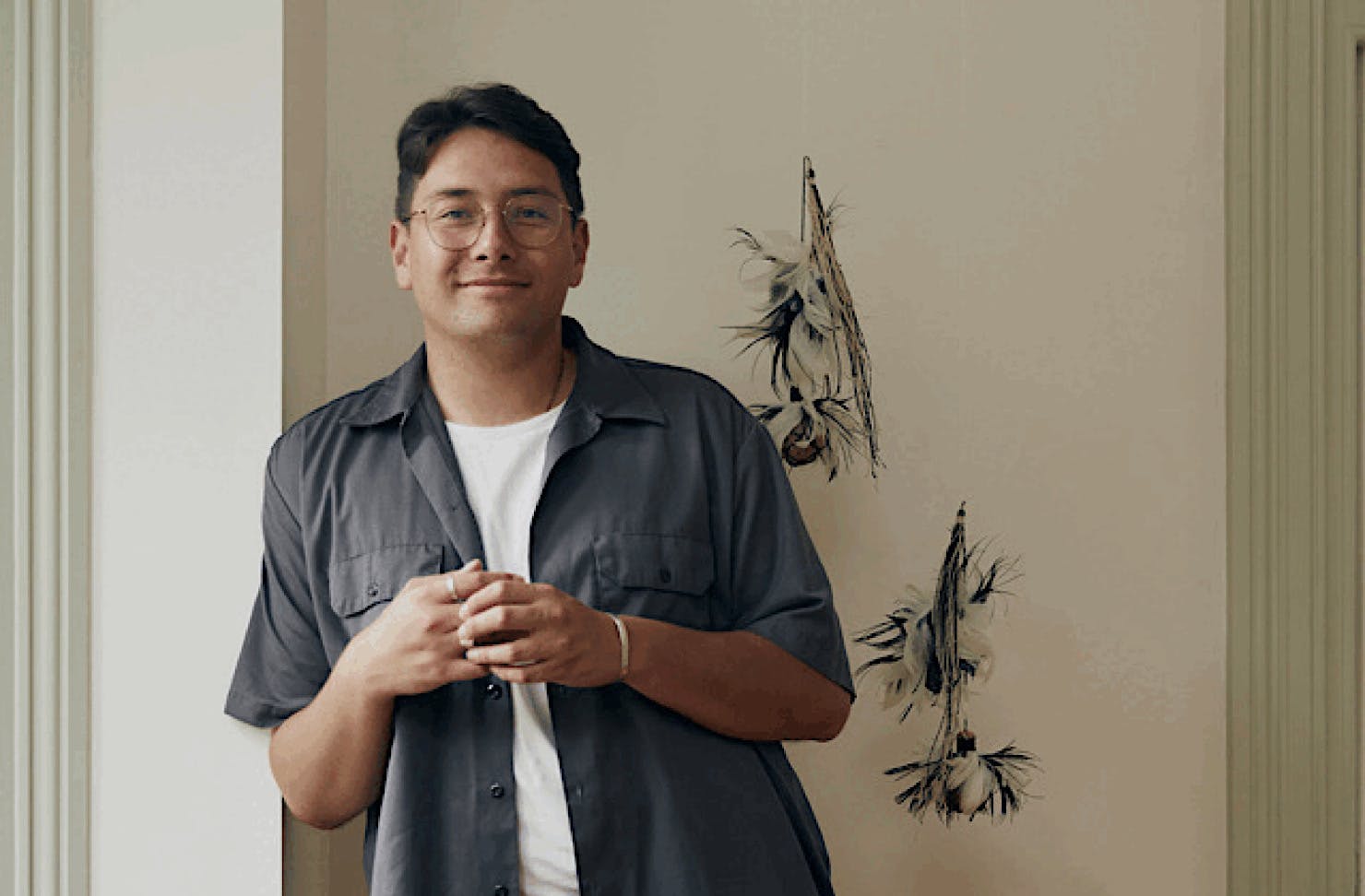 Hāmiora Bailey leans against a wall with a content expression. 